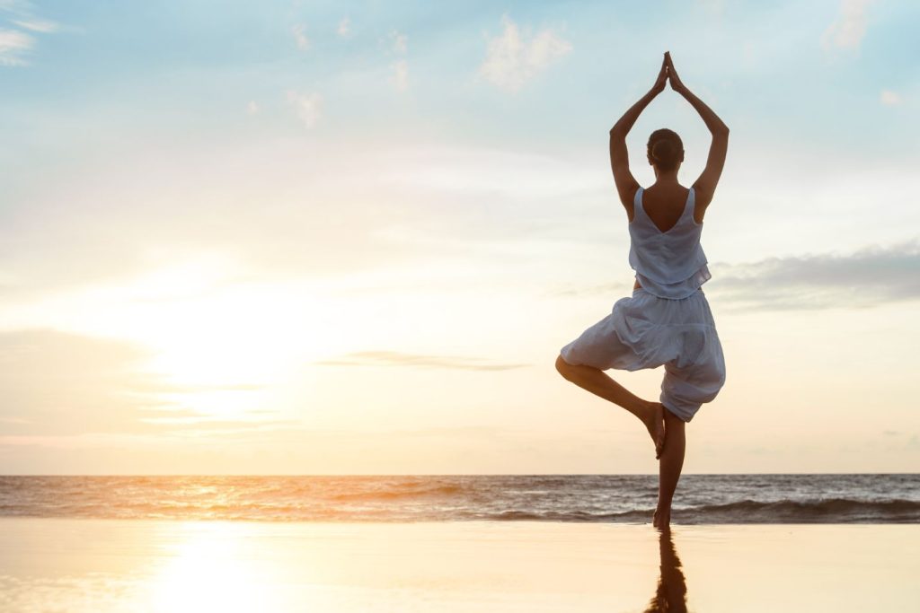 Woman standing on a beach doing yoga