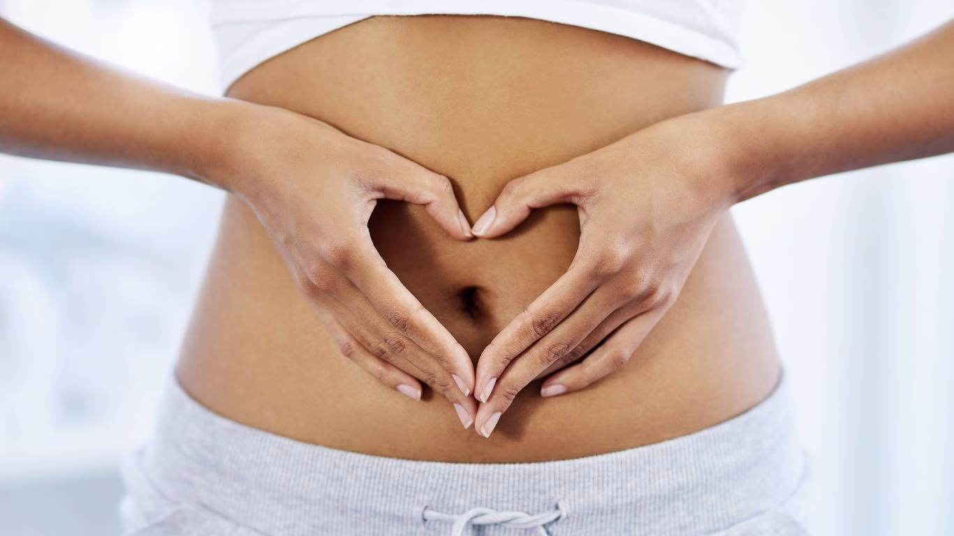Image of woman with her hands shaped like a love heart over her stomach