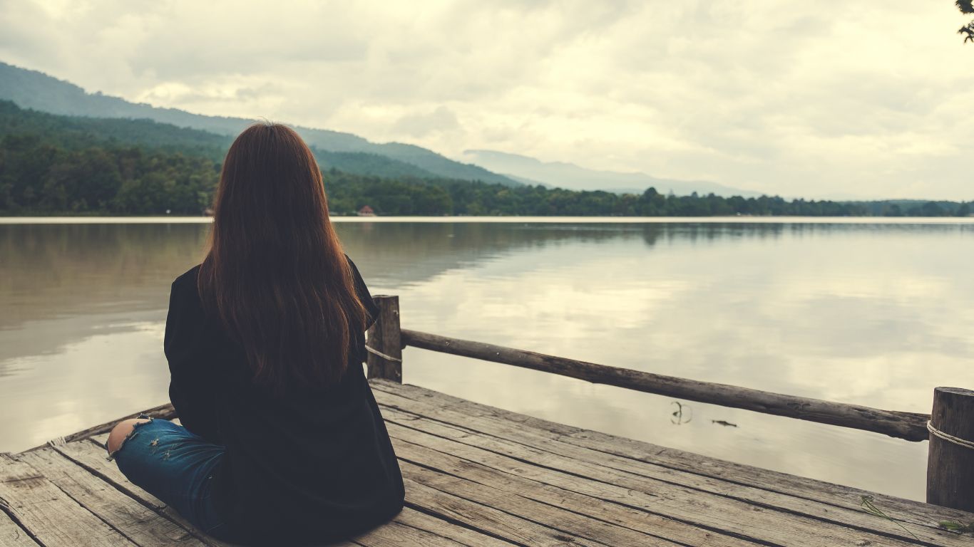 Image of woman sitting looking at calming mountain