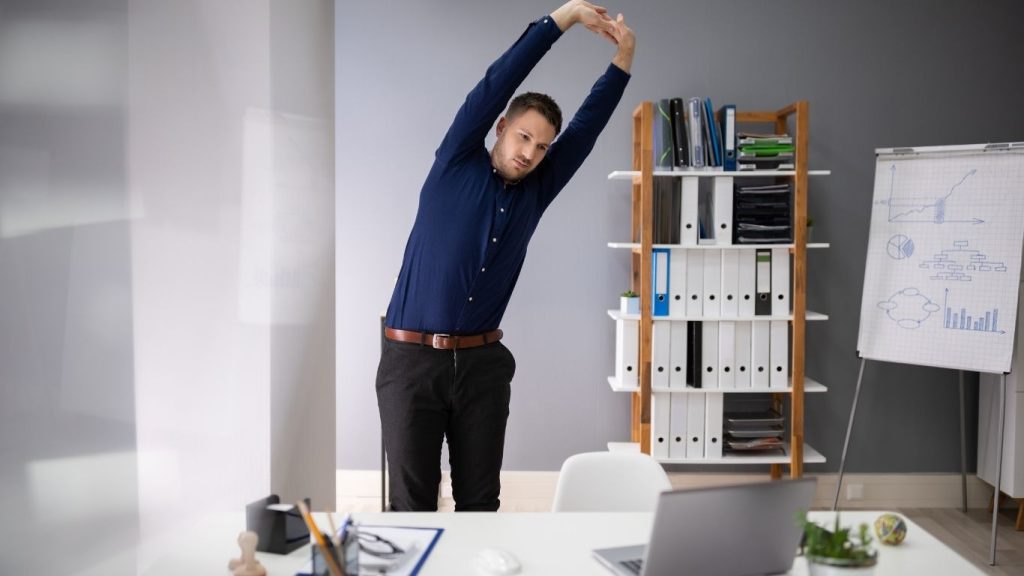 Man strteching behind a desk