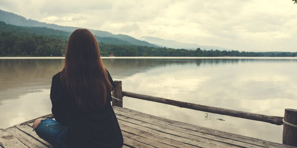Image of woman sitting looking at calming mountain