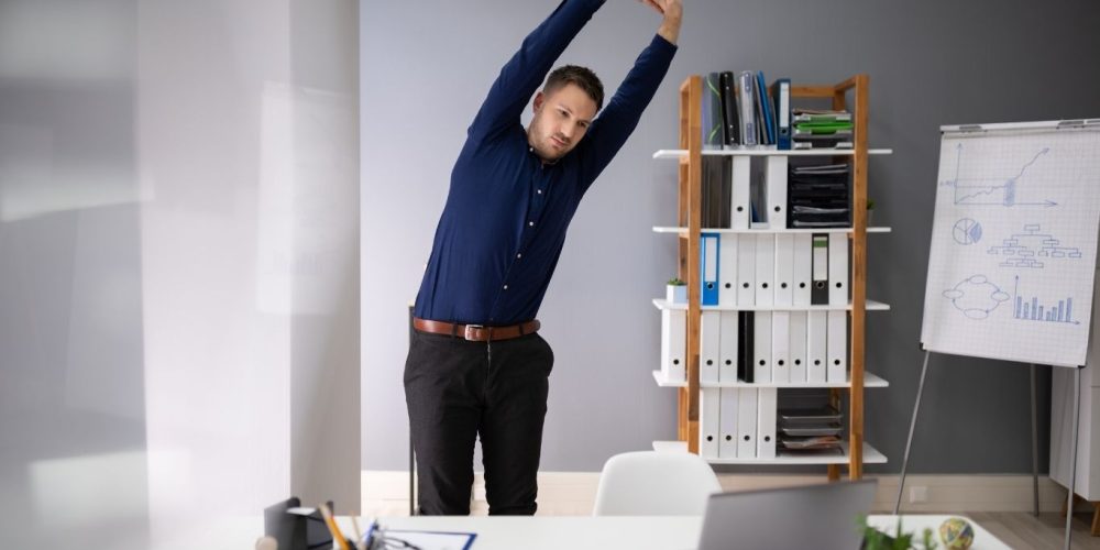 Man strteching behind a desk