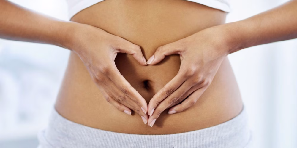 Image of woman with her hands shaped like a love heart over her stomach